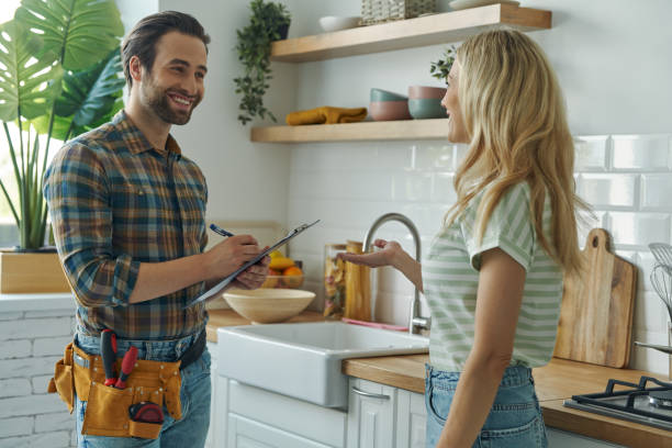 beautiful young woman talking to male plumber while standing at the kitchen beautiful young woman talking to male plumber while standing at the kitchen