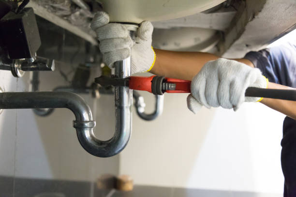plumber fixing white sink pipe with adjustable wrench.